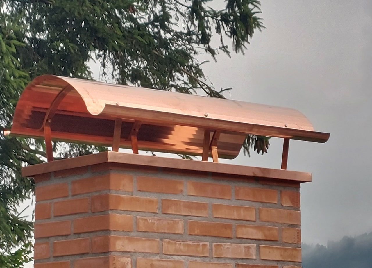 Kupferhaube auf gemauertem Kamin – Maßarbeit in edlem Material für sicheren Abzug bei jedem Wetter.