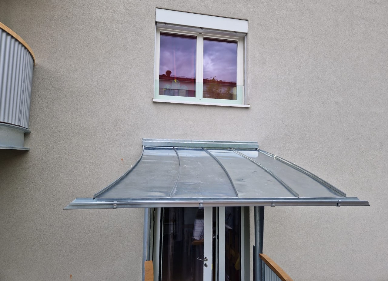 Individuell gefertigtes Vordach aus Metall mit elegant gebogener Form – eine maßgeschneiderte Lösung für optimalen Witterungsschutz und architektonische Klarheit.